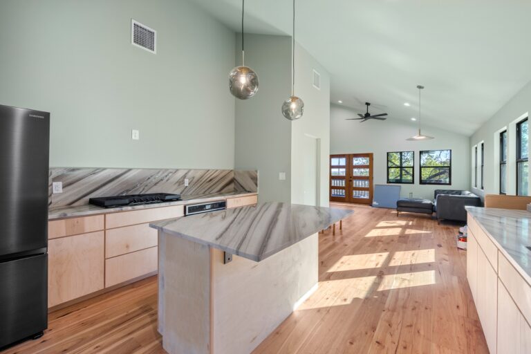 Open-concept kitchen remodel with marble waterfall island and wood floors